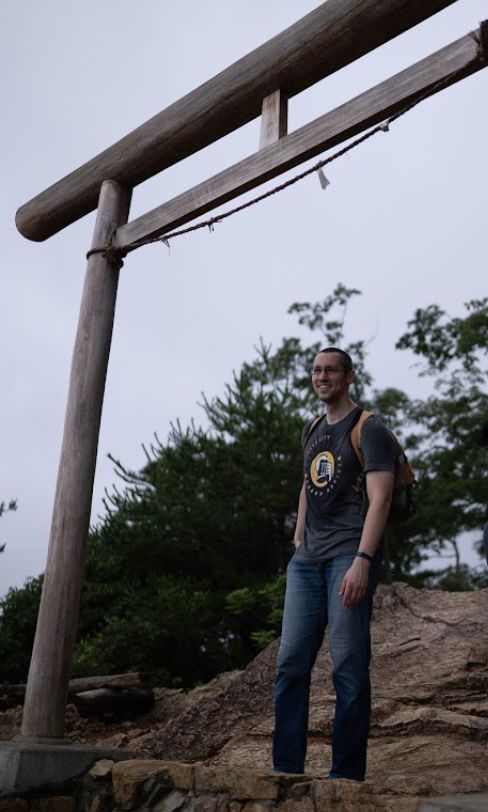 Caius standing on a mountain under a wooden torii